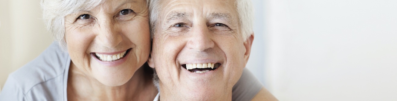 Older couple smiling and posing in a bright room 